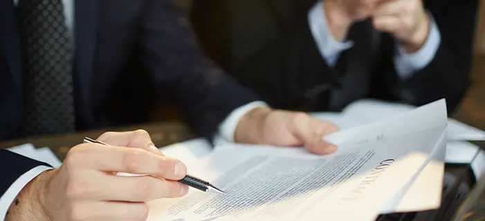 a man in a suit writing on a piece of paper, representing business legislation and legal documentation related to commercial activities.