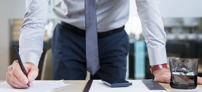a man in a suit writing on a piece of paper, representing labor law and legal documentation in the workplace.